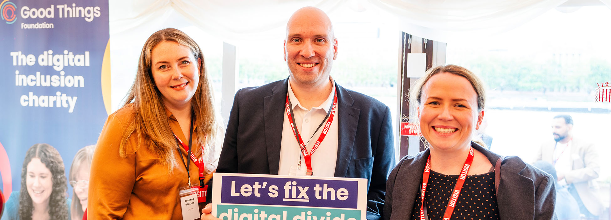 An event with three people holding up placards saying Fix The Digital Divide