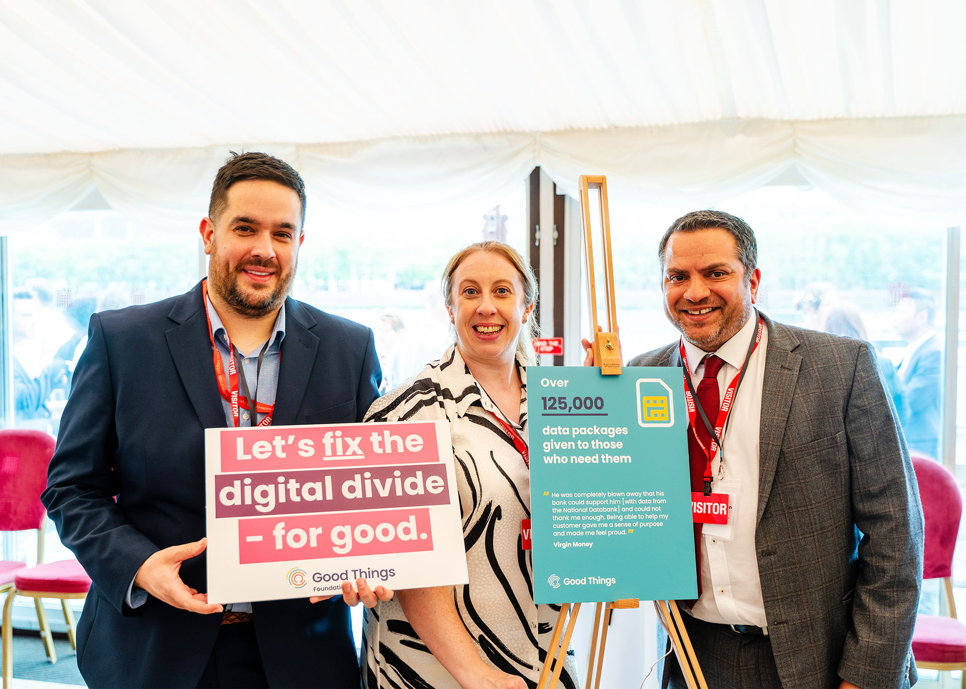 Three people holding fix the digital divide signs at an event